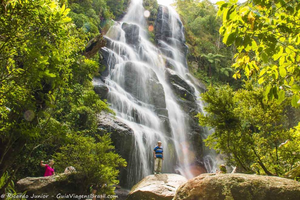 Imagem de um turista tirando foto na Cachoeira Véu de Noiva em Itatiaia.